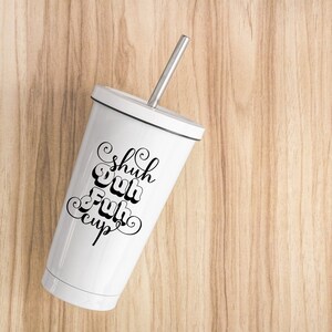 May include: White tumbler with a silver straw and the words "Shuh Duh Fuh Cup" in black script. The tumbler has a black rim and is set against a light wood grain background. A stylish and reusable drinkware item.
