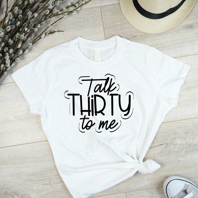 May include: White t-shirt with black text that reads "Talk Thirty to Me".