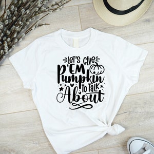 May include: White t-shirt with black text that reads "Let's give 'em pumpkin to talk about". A small pumpkin graphic is included in the text.