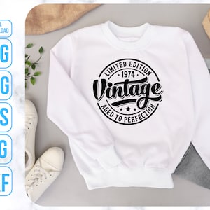 May include: White sweatshirt with a black circle graphic that says "Limited Edition - 1974 - Vintage Aged to Perfection".