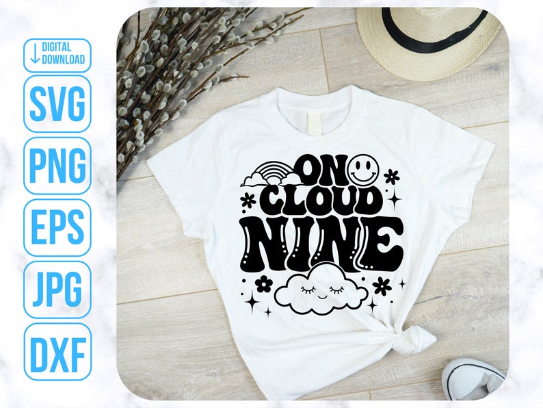 May include: White t-shirt with black text that reads "On Cloud Nine" in a retro font. The text is surrounded by a cloud, stars, and a rainbow.