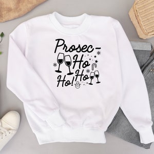May include: White sweatshirt with black text that reads "Prosec- Ho Ho Ho!" with a snowman and wine glasses.
