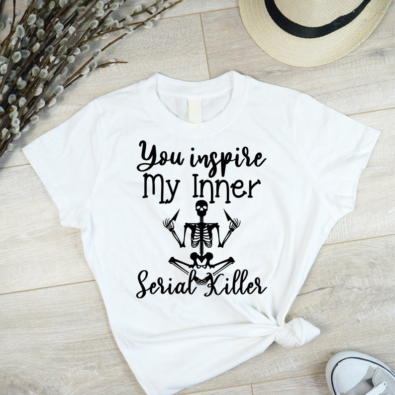 May include: White t-shirt with black text that reads "You inspire my inner Serial Killer" and a black skeleton illustration in a yoga pose.
