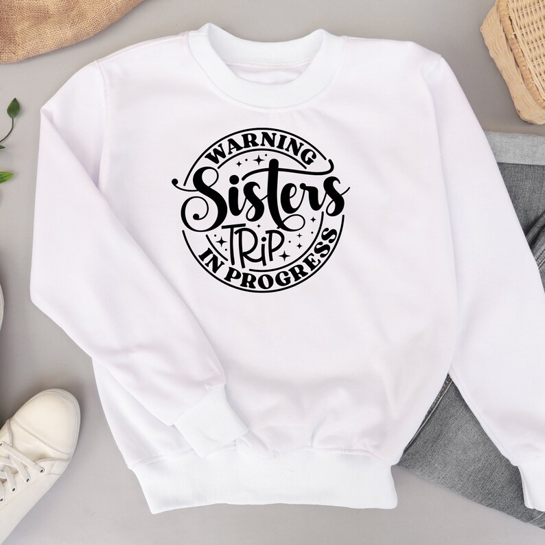 Puede incluir: Sudadera blanca con un gr&aacute;fico circular negro que dice "Warning Sisters Trip In Progress".