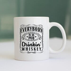 May include: White ceramic mug with a black design that says "Everybody in da pub drinkin' whiskey".