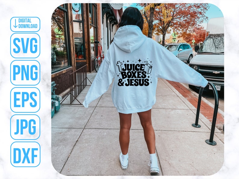 May include: A white hoodie with a black graphic that says "Juice Boxes & Jesus" on the back. The hoodie is being worn by a person walking down a sidewalk.
