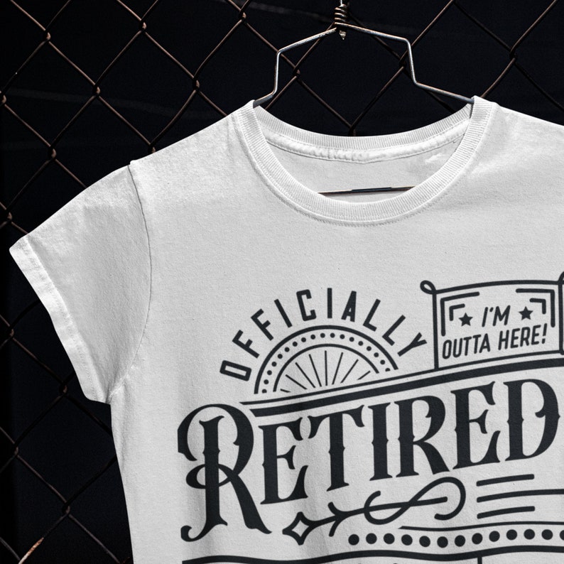 May include: White t-shirt with black text that reads "Officially Retired" with a decorative design and a small rectangle with the text "I'm Outta Here!"