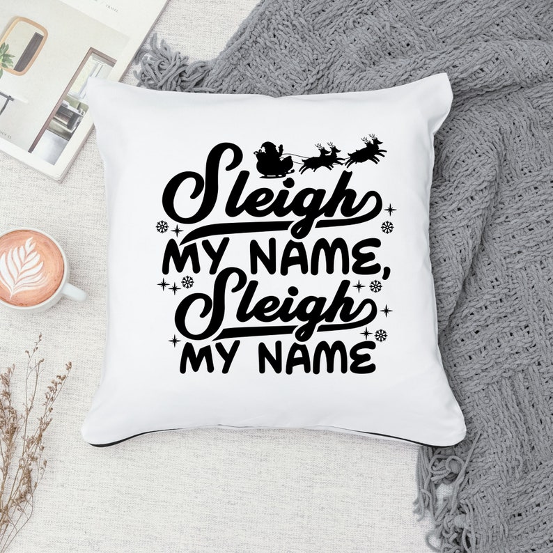 Puede incluir: Almohada blanca con texto negro que dice "Sleigh My Name, Sleigh My Name". El texto est&aacute; en una fuente festiva e incluye una peque&ntilde;a imagen de Santa Claus en su trineo con renos.