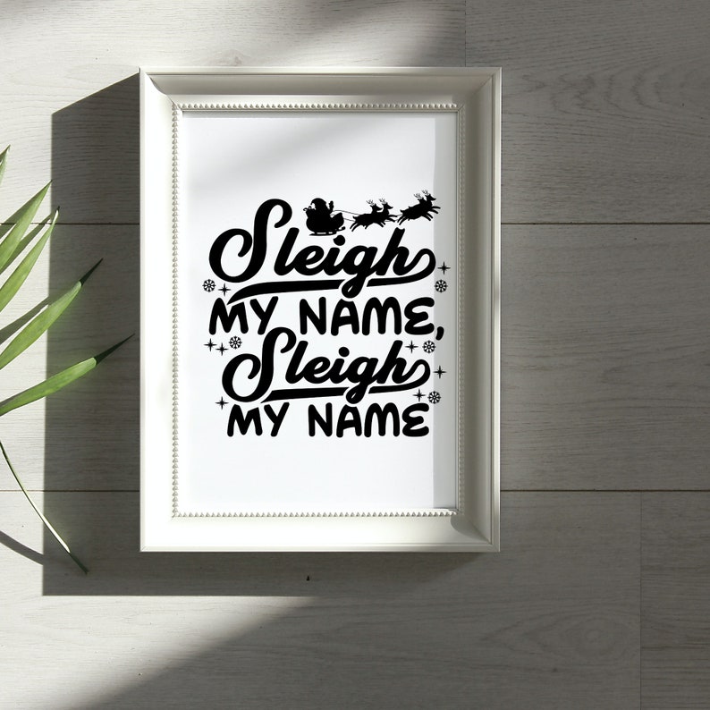 Puede incluir: Impresi&oacute;n enmarcada en blanco con texto negro que dice "Sleigh My Name, Sleigh My Name" con una silueta de Pap&aacute; Noel en un trineo tirado por renos sobre el texto.