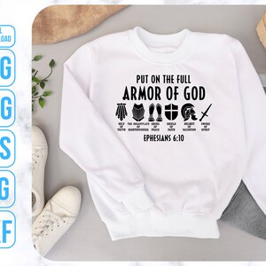Puede incluir: Sudadera blanca con texto negro que dice "Ponte la armadura completa de Dios" con un gr&aacute;fico de la armadura de Dios y la escritura Efesios 6:10.