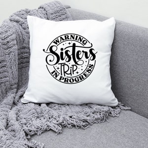Puede incluir: Coj&iacute;n blanco con texto negro que dice "Warning Sisters Trip in Progress" en un c&iacute;rculo con estrellas.