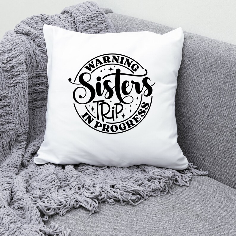 Puede incluir: Coj&iacute;n blanco con texto negro que dice "Warning Sisters Trip in Progress" en un c&iacute;rculo con estrellas.