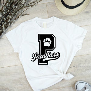 May include: White t-shirt with a black and white graphic of a letter P with a paw print inside and the word "Panthers" in a black script font.