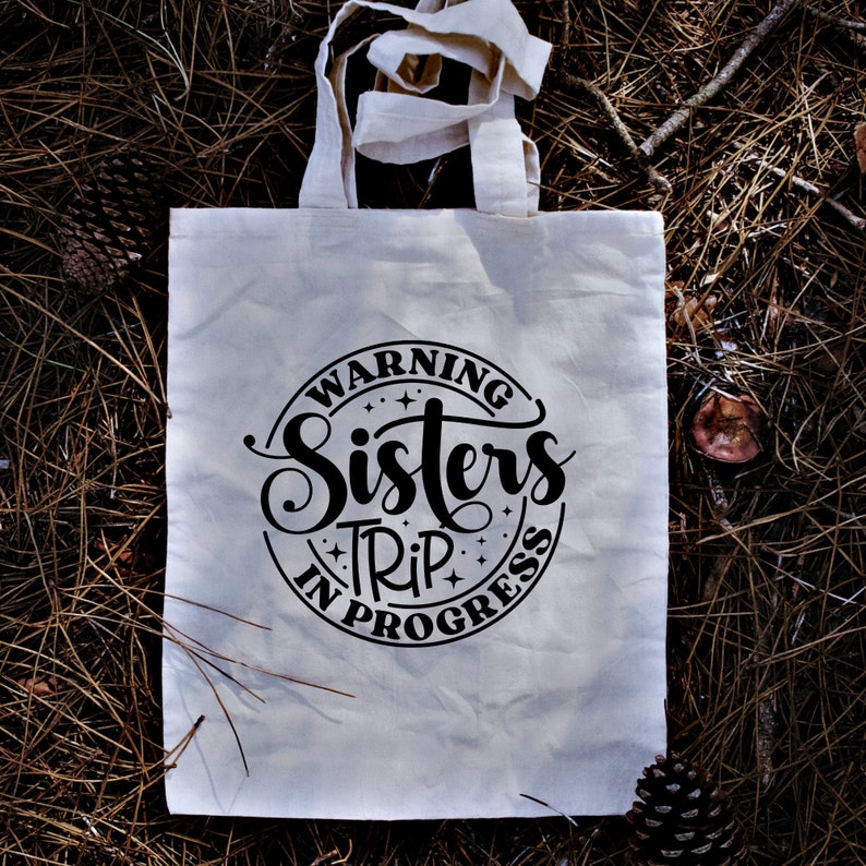 Puede incluir: Bolsa de tela blanca con texto negro que dice "Warning Sisters Trip in Progress" en un c&iacute;rculo con estrellas.