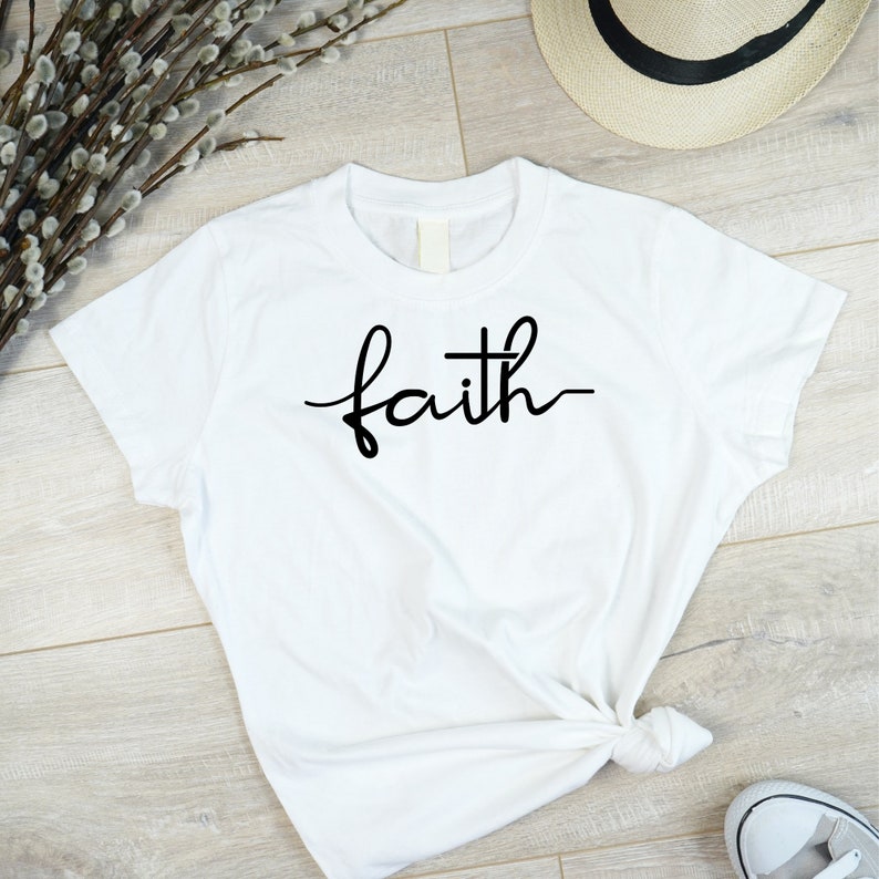 May include: White t-shirt with the word "faith" written in black cursive script.