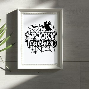 Pu&ograve; includere: Una stampa incorniciata bianca con un'illustrazione in bianco e nero di un fantasma, una ragnatela, pipistrelli e stelle. Il testo "Spooky Teacher" &egrave; scritto in un font stilizzato.