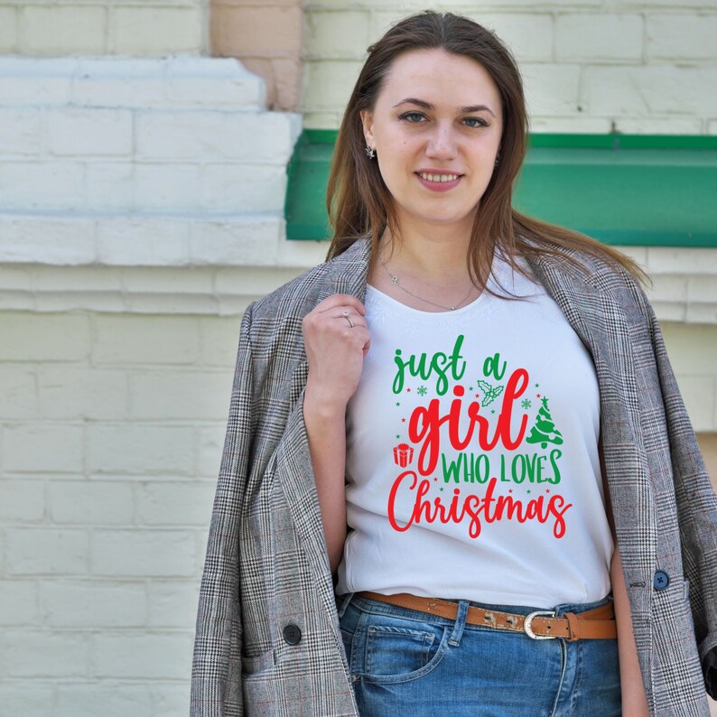 Pu&ograve; includere: Maglietta bianca con una grafica rossa e verde che dice "Just a girl who loves Christmas".