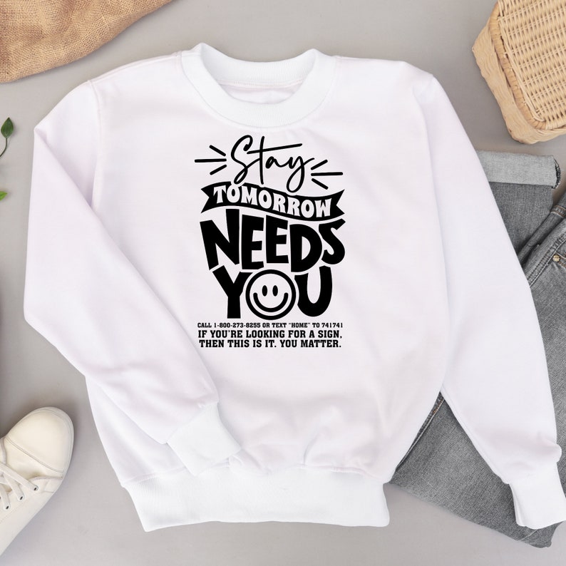 May include: White sweatshirt with black text that reads "Stay Tomorrow Needs You" with a smiley face. The text also includes a phone number and the message "If you're looking for a sign, then this is it. You matter."