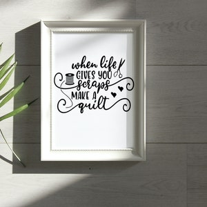 May include: White framed print with black text that reads "when life gives you scraps make a quilt". The text is surrounded by decorative swirls and includes a spool of thread and a pair of scissors.