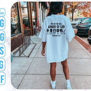 Puede incluir: Una camiseta blanca con texto negro que dice "Ponte la armadura completa de Dios, Efesios 6:10". El texto est&aacute; rodeado de peque&ntilde;os iconos negros de armadura.