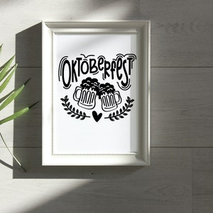 May include: A white framed print with black text that says "Oktoberfest" and a graphic of two beer steins with hearts.