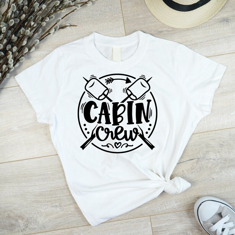 May include: White t-shirt with a black graphic design of crossed marshmallow roasting sticks and the text "Cabin Crew".