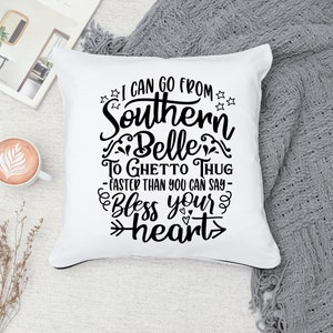 May include: White throw pillow with black text that reads "I can go from Southern Belle to Ghetto Thug - faster than you can say - Bless your heart".