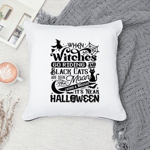 K&ouml;nnte beinhalten: Ein wei&szlig;es Kissen mit schwarzem Text, der lautet "When Witches Go Riding and Black Cats Are Seen The Moon's Laughs & Whispers It's Near Halloween". Der Text ist umgeben von einer Hexe auf einem Besen, einer schwarzen Katze, einem Halbmond und Flederm&auml;usen.