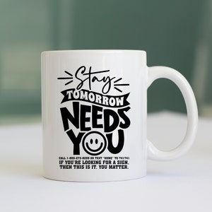 May include: White ceramic coffee mug with black text that reads "Stay Tomorrow Needs You" with a smiley face. The text also includes a phone number and a message that reads "If you're looking for a sign, then this is it. You matter."