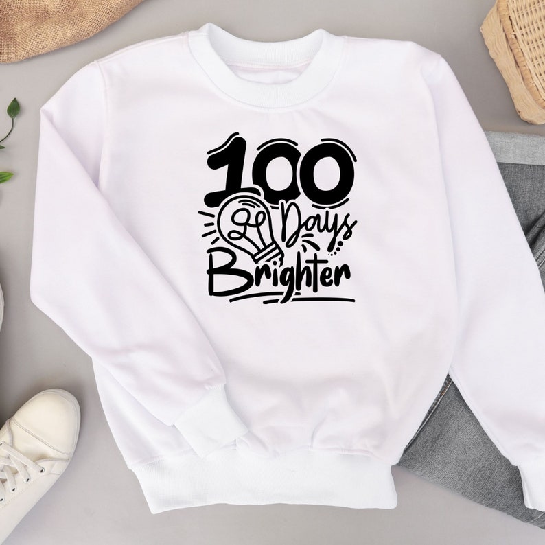 May include: White sweatshirt with black text that reads "100 Days Brighter" with a lightbulb graphic.