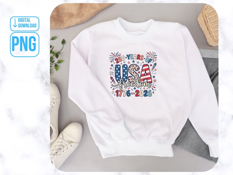 May include: A white sweatshirt featuring a vibrant graphic commemorating 250 years of USA freedom. The design incorporates the text "250 Years of USA Freedom 1776-2026" in red, white, and blue, with star and firework motifs. The sweatshirt is shown on a neutral background.