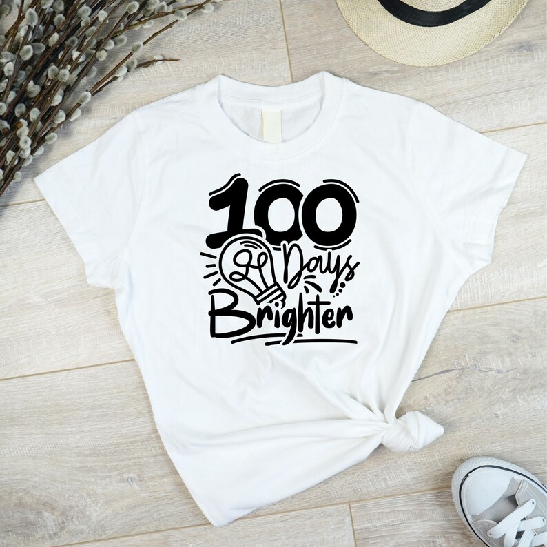 May include: White t-shirt with black text that reads "100 Days Brighter" with a lightbulb graphic.