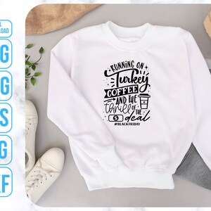 K&ouml;nnte beinhalten: Wei&szlig;er Pullover mit schwarzem Text, der "Running on Turkey Coffee and the thrill of the deal #BlackFriday" lautet.