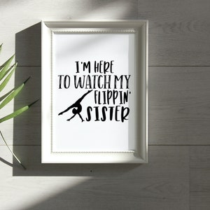 May include: White framed print with black text that reads "I'm here to watch my flippin' sister". A black silhouette of a gymnast performing a back handspring is in the center of the text.