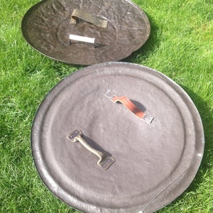 May include: Two round, brown shields with metal handles. The shields are made of a textured material and have a slightly raised edge.