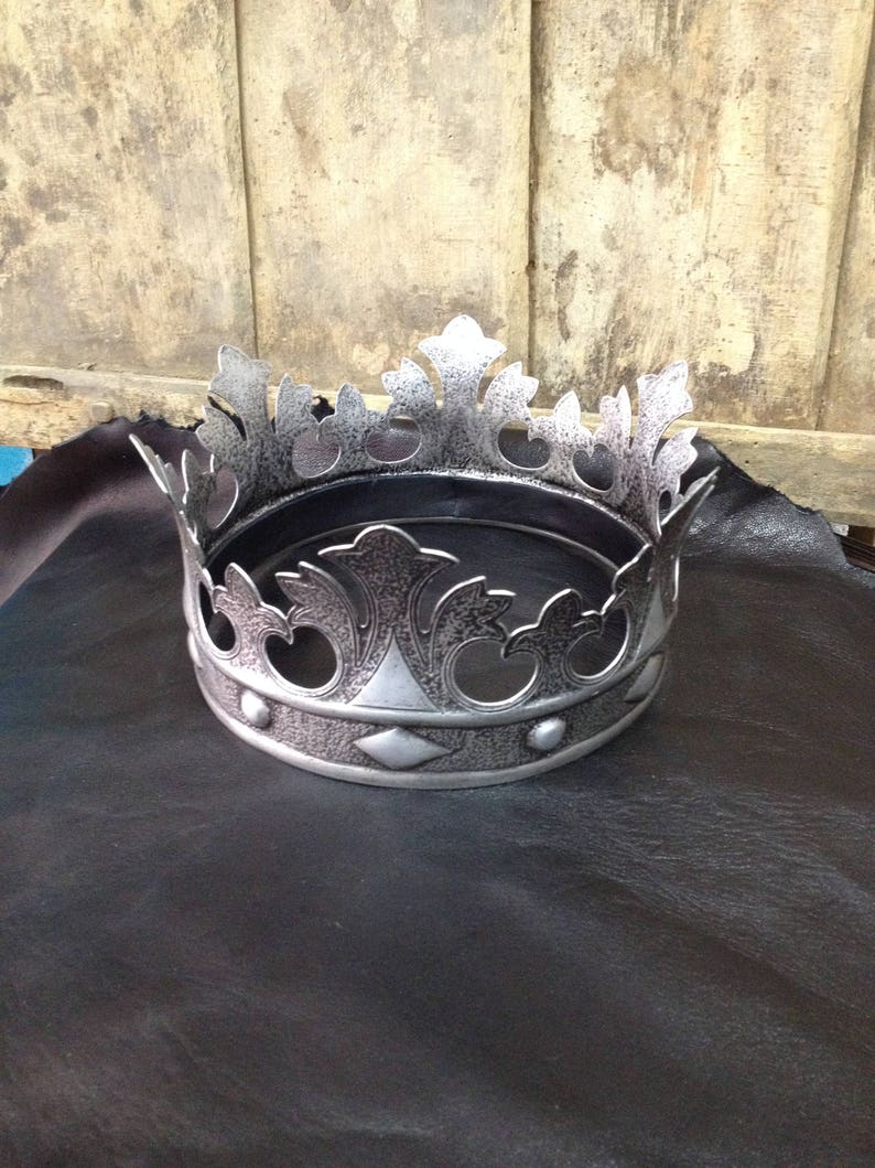 Peut inclure: Une couronne argent&eacute;e avec un design d&eacute;coratif. La couronne a un sommet pointu et une base circulaire.