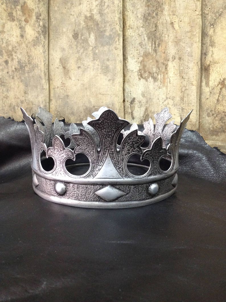 Peut inclure: Une couronne argent&eacute;e avec un motif d&eacute;taill&eacute; de feuilles et un motif en forme de diamant. La couronne a une surface textur&eacute;e et est en m&eacute;tal.
