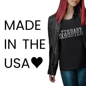 A person with red hair wearing a black leather jacket and a black t-shirt with the text "MADE IN THE USA" and a heart symbol.