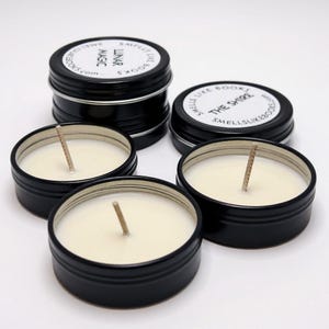 a collection of black tin candle jars with white candle wax, arranged on a white background.