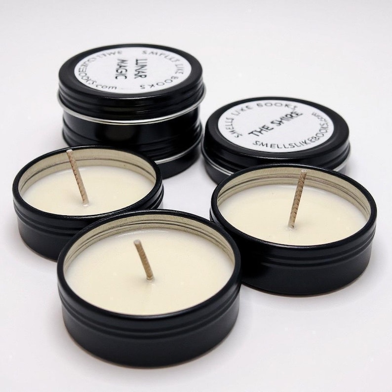a collection of black tin candle jars with white candle wax, arranged on a white background.