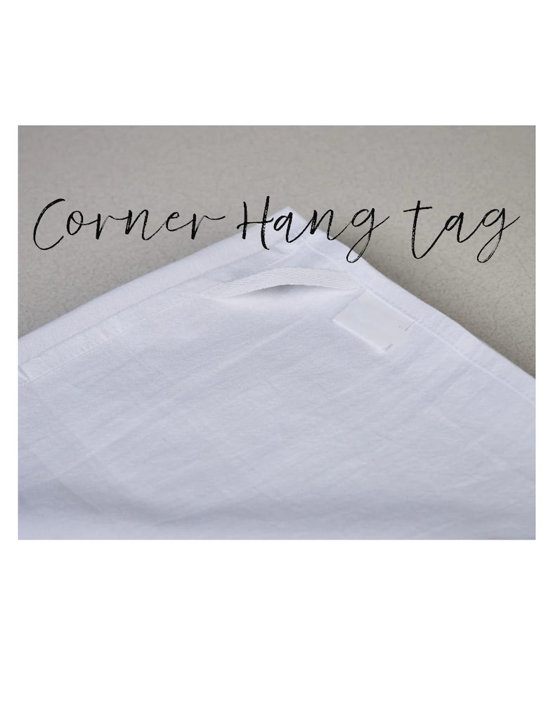 May include: White corner hang tag with the text "Corner Hang tag" in a script font. The tag is made of a textured fabric and has a small rectangular label attached.