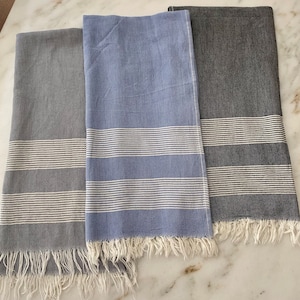 May include: Three striped towels in gray, blue, and black with white stripes. The towels have a fringe border.