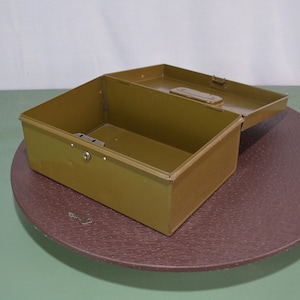 May include: A green metal toolbox with a hinged lid and a lock. The toolbox is open and empty.