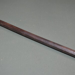 May include: A dark brown, wooden, tapered dowel rod with a slightly rounded end.