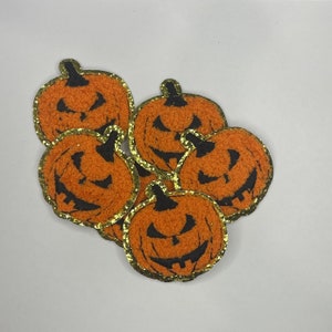 May include: Five orange felt pumpkin patches with black felt faces and gold glitter trim.