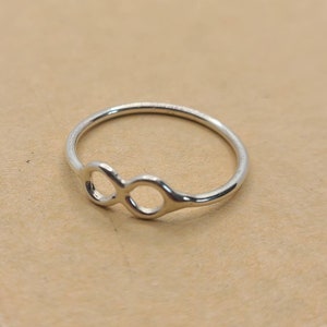 May include: A silver infinity symbol ring. The ring is simple and delicate, with a smooth finish.