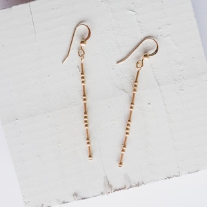 May include: A pair of gold dangle earrings with a beaded chain design.