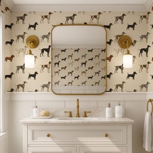 May include: A bathroom with a vanity, mirror, and dog-themed wallpaper. The wallpaper features various dog breeds in brown, black, and gray on a cream background. The vanity has a white countertop, gold fixtures, and a gold-framed mirror.