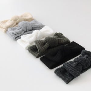 Puede incluir: Una colecci&oacute;n de seis diademas de punto en varios colores. Las diademas est&aacute;n dispuestas en fila, mostrando tonos crema, gris, blanco, verde oscuro, negro y gris carb&oacute;n. Cada diadema presenta un dise&ntilde;o de lazo anudado.