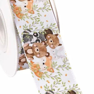 May include: White ribbon with a repeating pattern of cartoon bears, raccoons, and foxes in a woodland setting. The animals are brown, black, and orange. The ribbon is on a white spool.